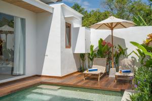 un patio avec des chaises et un parasol à côté d'une piscine dans l'établissement Villa Eden at Nyanyi, à Canggu 35 autres photos