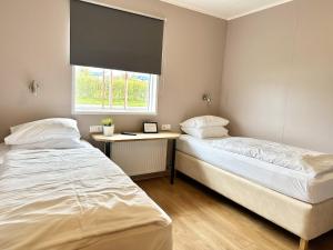two beds in a room with a desk and a window at ALBERT Guesthouse in Hvammstangi
