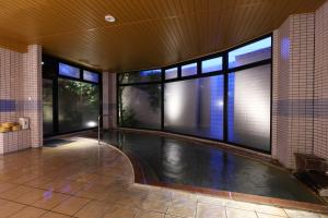 an indoor swimming pool in a building with windows at Suwakoen in Suwa