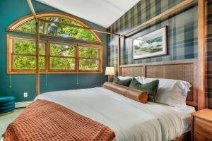a bedroom with a large bed and two windows at 6BR Houghton Lake House with Indoor Pool, Hot Tub and Golf Simulator in Prudenville +76 photos