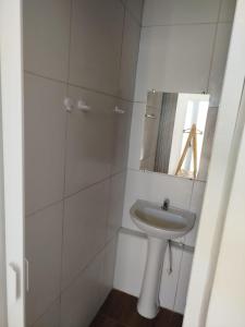 ein weißes Badezimmer mit Waschbecken und Spiegel in der Unterkunft Hospedagem da barra suites,praia barra grande,caminho de moises e antunes in Maragogi