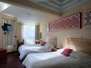 una camera d'albergo con due letti e una televisione di J&K Suite a San Cristóbal de Las Casas