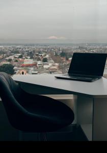 a laptop sitting on top of a desk with a chair at Depto Cómodo y Equipado en el Centro de Chillan con Estacionamiento in Chillán