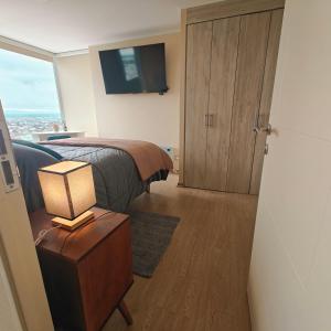 a bedroom with a bed and a television and a table with a lamp at Depto Cómodo y Equipado en el Centro de Chillan con Estacionamiento in Chillán