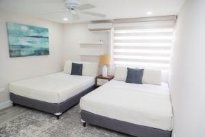 two beds in a room with a window at The View, Goodwood Park Lux Townhouse in Diego Martin