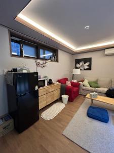 a living room with a black refrigerator and a couch at Guest House Dalggume in Mokpo