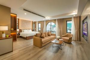 a living room with a couch and a bed in a room at Gilson Hanoi Hotel in Hanoi