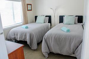 ein Schlafzimmer mit zwei Betten und einem Fenster in der Unterkunft Monarch Cottage on the Estuary in Athenree