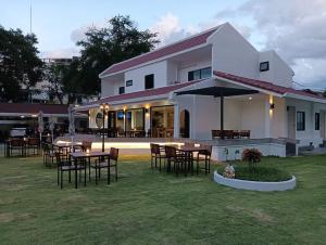 a white building with tables and chairs in a yard at The European Chiang Mai in Chiang Mai