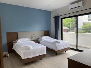 two beds in a room with a large window at The European Chiang Mai in Chiang Mai