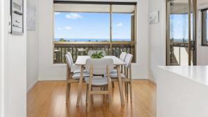a dining room with a table and chairs and a window at Sea For Days - Panoramic Bay Views in Rye in Rye