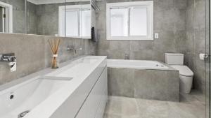 a white bathroom with a tub and a toilet at Sea For Days - Panoramic Bay Views in Rye in Rye +13 photos