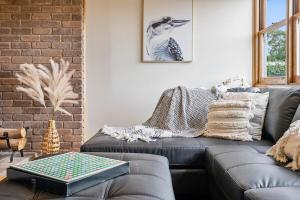 a living room with a leather couch and a brick wall at Beach Holiday Home-Close to Airport-3 Bed & 2 Bath in Lauderdale