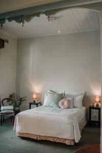 a bedroom with a large white bed with pillows at La Cochon Rose Motel in Saint Arnaud