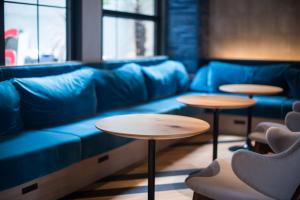 a room with a blue couch and two tables at Hotel She, Osaka in Osaka