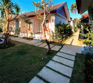 a house with a tree in front of a walkway at D'padang villa & Homestay in Uluwatu