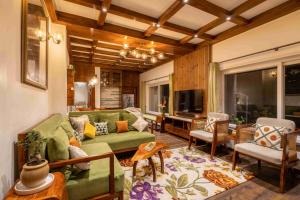 a living room with a green couch and chairs at amã Stays & Trails Barefoot Bungalow, Dhanaulti in Dhanaulti
