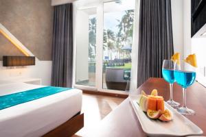 a hotel room with a bed and two glasses of wine at Camelot Beach Hotel in Negombo