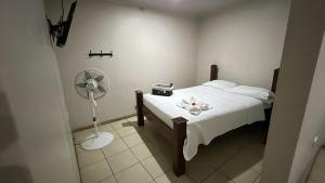a bedroom with a white bed and a fan at Rivera Family Airport Apartments in Santiago Este