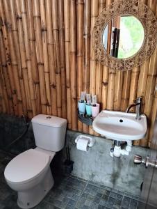 a bathroom with a toilet and a sink and a mirror at East Holiday Resort Moalboal in Moalboal