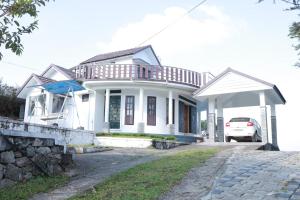a white house with a car parked in front of it at HILLFORT HOMESTAY in Vagamon +21 photos