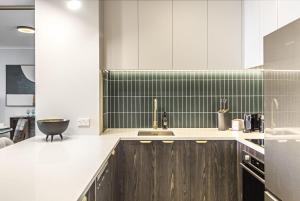 eine Küche mit weißen Schränken und einer Spüle in der Unterkunft Luxurious Harbour View Apartment in Downtown in Auckland + 12 Fotos