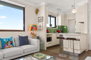 シドニーにあるPristine 2-Bed With Expansive Beach Viewsのソファとキッチンのあるリビングルーム