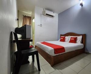 a bedroom with a bed and a chair and a television at Hotel O Ban Cheong in Kangar