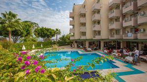a view of a hotel with a swimming pool and purple flowers at Viking Nona Beach in Kemer