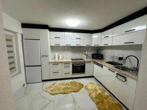 a kitchen with white cabinets and a rug on the floor at JB apartman Živinice in Živinice