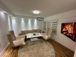 a living room with a couch and a table and chairs at JB apartman Živinice in Živinice