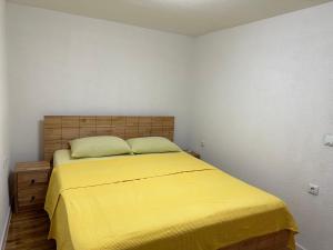 a bedroom with a bed with a yellow blanket at JB apartman Živinice in Živinice
