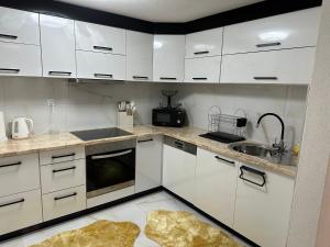 a kitchen with white cabinets and a sink at JB apartman Živinice in Živinice +10 photos