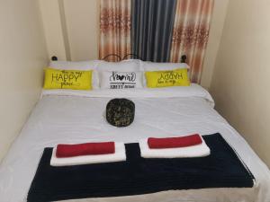 a bed with a black and red tie on it at Micasa Homes BNB in Kihingo