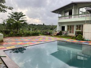 a swimming pool with a colorful rug in front of a house at Mikunj Farms Karjat in Karjat