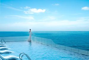 een vrouw aan de rand van een zwembad met uitzicht op de oceaan bij Vias Hotel Vung Tau in Vung Tau