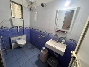 a blue and white bathroom with a toilet and a sink at Mikunj Farms Karjat in Karjat +9 photos
