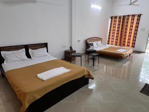 a bedroom with two beds and a table and a window at Mikunj Farms Karjat in Karjat