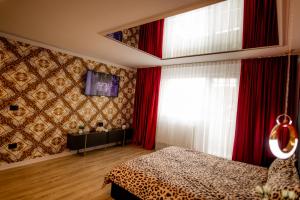 a bedroom with red curtains and a bed and a television at Desire Loft in Alba Iulia