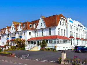 a large white building with a car parked in a parking lot at The Esplanade Hotel by Compass Hospitality in Paignton