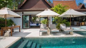 une piscine avec chaises longues et parasols à côté d'une maison dans l'établissement Chic Baan Capo - Luxury Four Bedroom Beachfront Villa, à Bangrak Beach
