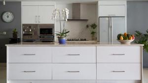 - une cuisine avec des placards blancs et un comptoir avec un bol de fruits dans l'établissement Chic Baan Capo - Luxury Four Bedroom Beachfront Villa, à Bangrak Beach 12 autres photos