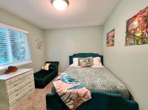 a bedroom with a bed and a chair at Forest cottage - secluded, hot tub, walk to beach in Rockaway Beach