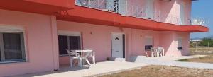 a pink building with chairs and a table on the porch at Pefki Apartment 9 in Artemísion