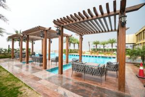 a pool at the resort with chairs and a wooden pergola at Seven Seas Hotel in New Delhi