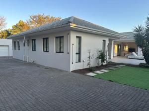 Luxury holiday home 3 bedroom, 3 bathroom house in Nahoon في شرق لندن: بيت أبيض مع ممر أمامه