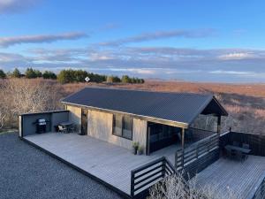 a house with a wooden deck and a roof at Cozy 3BR Summerhouse with Hot Tub in South Iceland in Selfoss