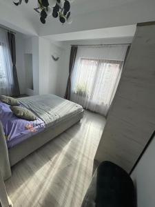 a bedroom with a bed and a large window at Jules Cozy Place in Bucharest