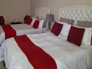 een slaapkamer met twee bedden met rode en witte kussens bij Serene Pastures in Midrand