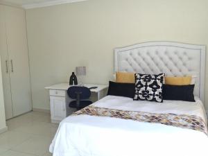 een slaapkamer met een wit bed en een bureau bij Serene Pastures in Midrand